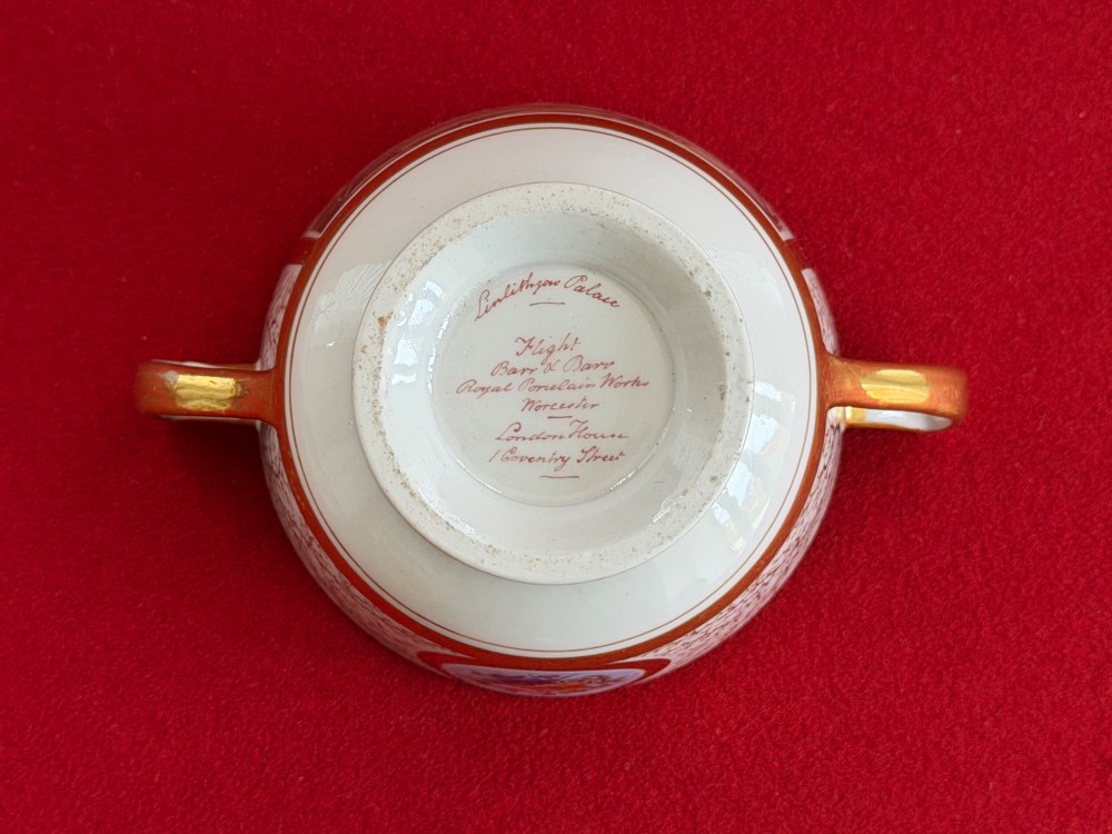 An antique Flight, Barr and Barr Worcester porcelain covered chocolate cup with two handles and matching saucer, decorated with hand-painted landscape and floral panels amid gold vermicelli detailing. View XI