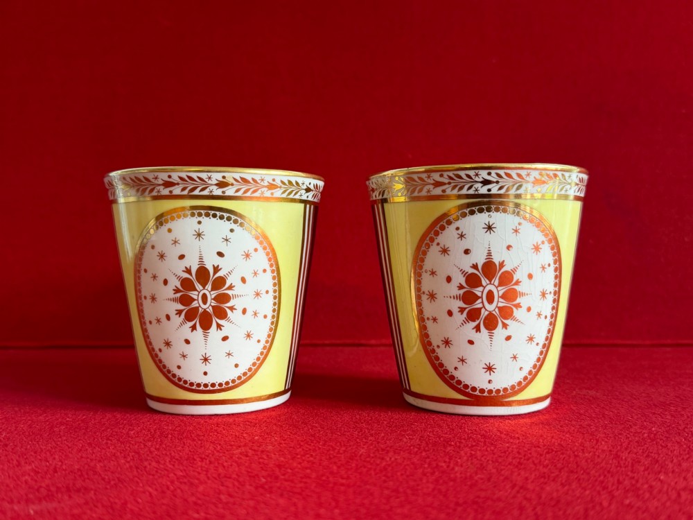A pair of yellow antique porcelain beakers featuring hand-painted exotic birds within oval gilt reserves and gilded leaf borders along the top rim. View III