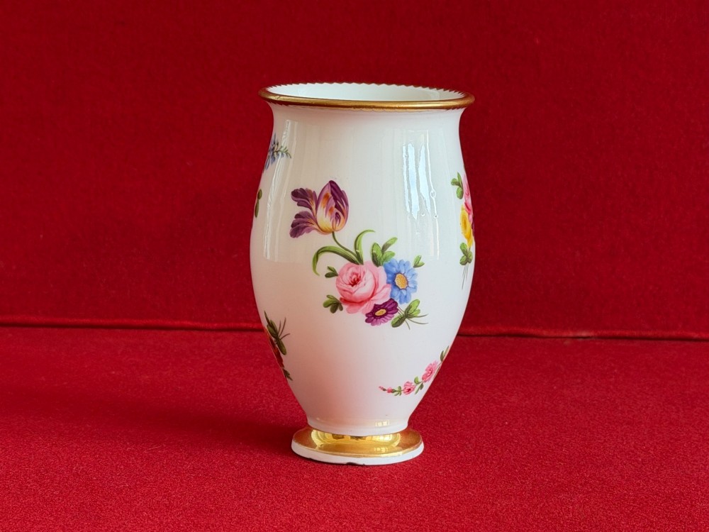 A white porcelain spill vase featuring hand-painted floral sprays, a flared lip, and gilded accent bands along the rim and base. View V