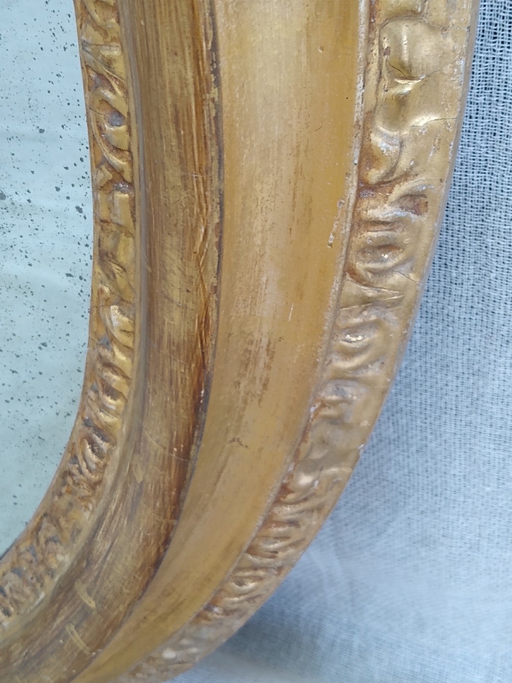 An antique 19th-century Italian oval giltwood wall mirror with an ornate carved scroll cresting pediment. View XI