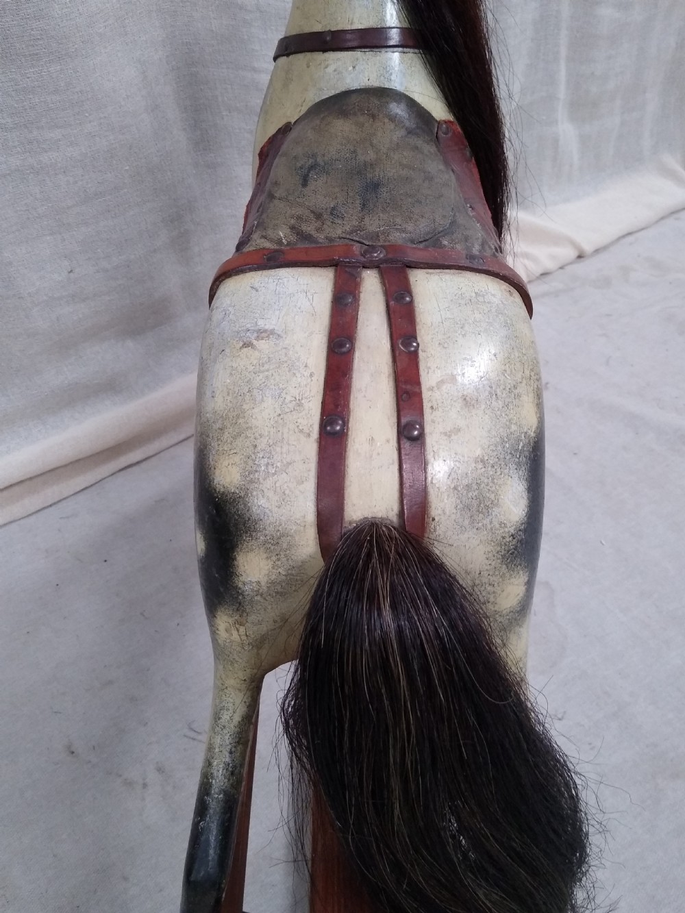 An antique carved wooden rocking horse with a painted dapple finish, leather saddle, and real horsehair mane, mounted on a wooden safety stand. View VIII