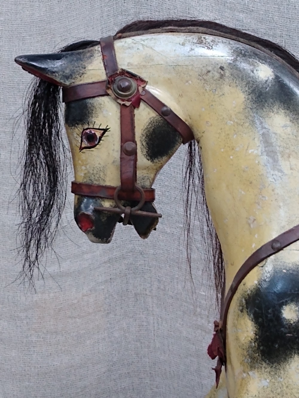 An antique carved wooden rocking horse with a painted dapple finish, leather saddle, and real horsehair mane, mounted on a wooden safety stand. View IX