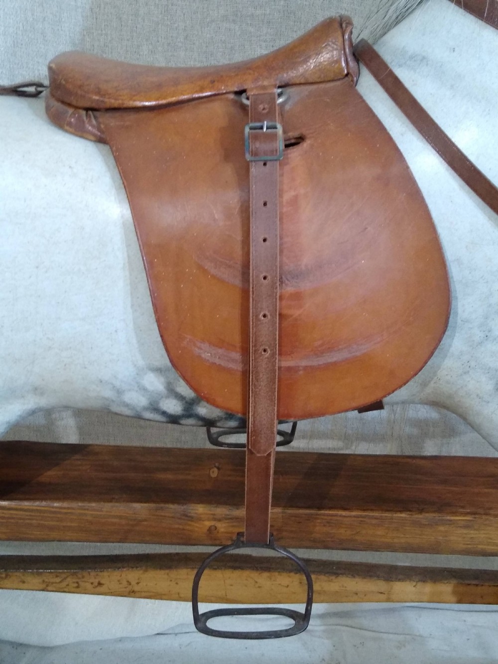 An antique carved wooden rocking horse with a dapple grey painted finish, real hair mane, leather saddle, and bridle, mounted on a wooden safety stand. View V