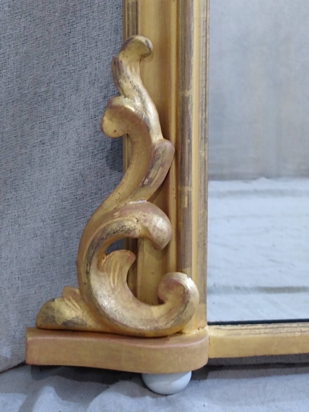 A rectangular Victorian overmantel mirror featuring a gilt frame with side scroll brackets and shaped upper inner corners. View IV