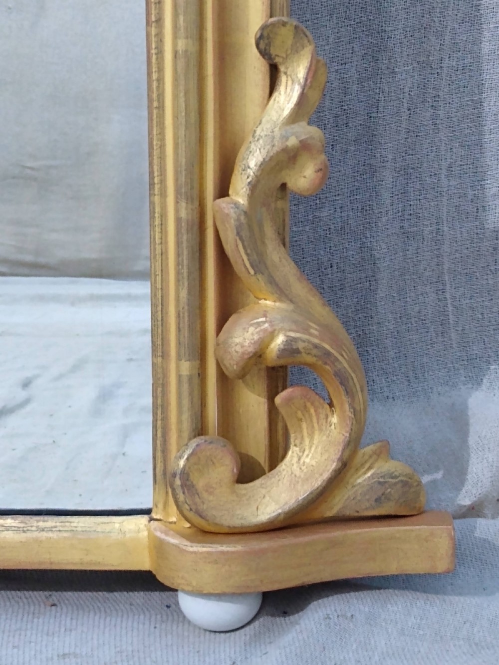 A rectangular Victorian overmantel mirror featuring a gilt frame with side scroll brackets and shaped upper inner corners. View V