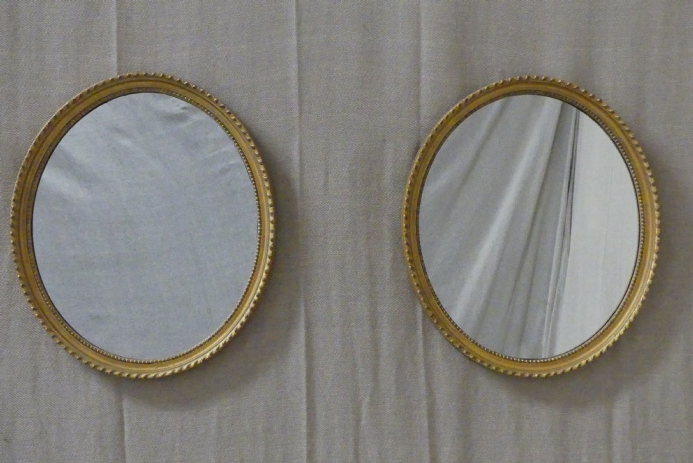 A pair of matching late 19th-century oval mirrors featuring gilded timber frames with beaded edge moulding.
