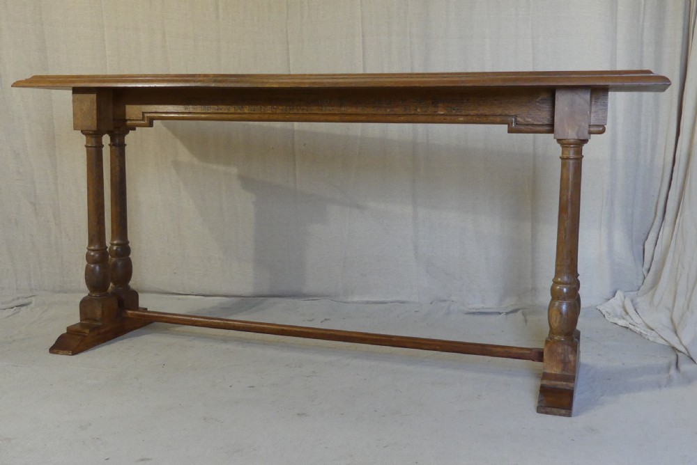A long, narrow antique oak console table featuring a carved frieze, turned end supports, and a low central stretcher.
