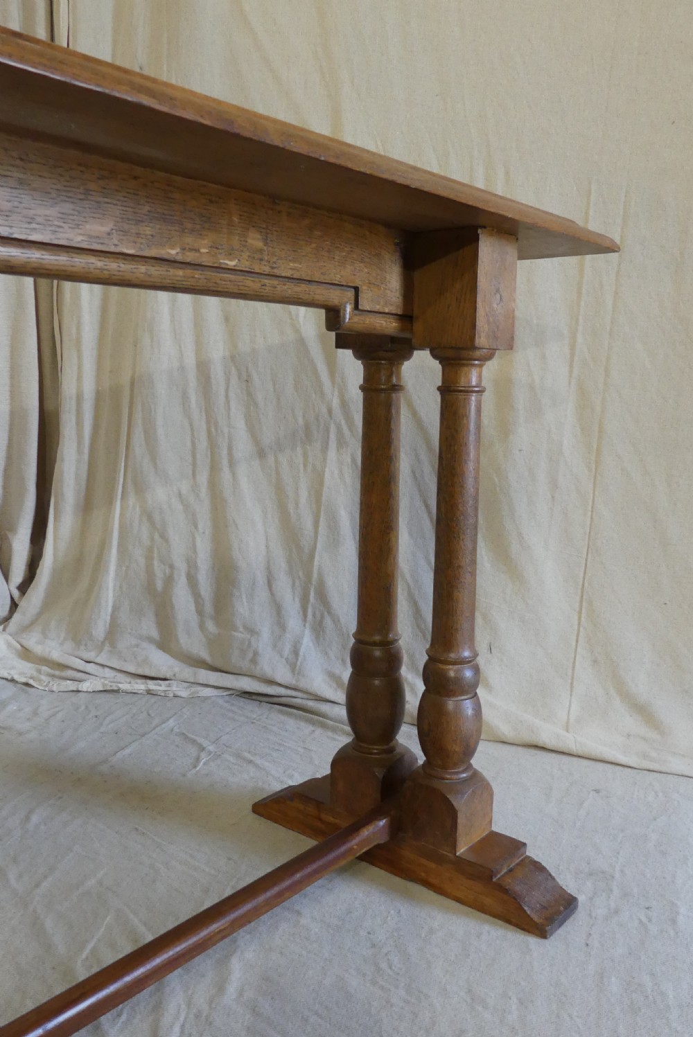 A long, narrow antique oak console table featuring a carved frieze, turned end supports, and a low central stretcher. View IX