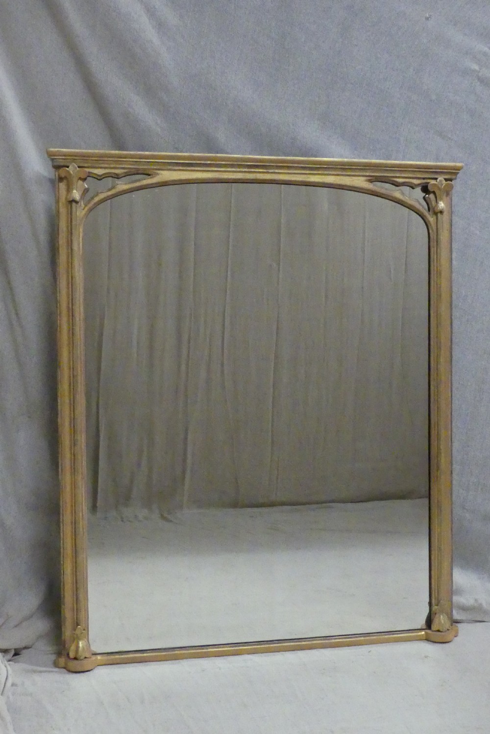 A large late 19th-century rectangular giltwood overmantel mirror featuring an arched inner frame with spandrel detailing.