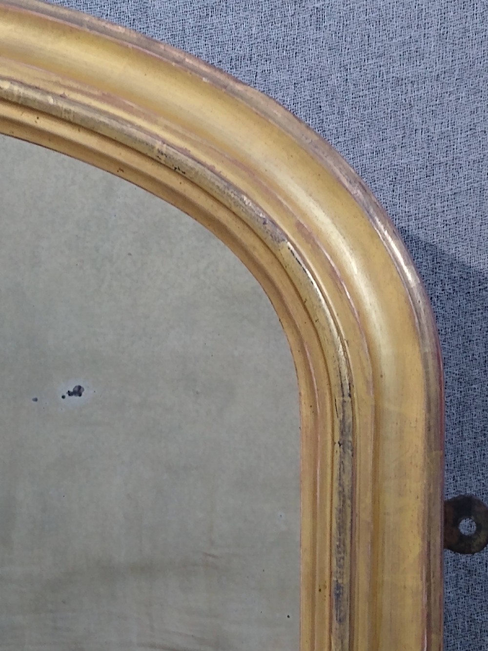 An antique Victorian arched overmantel mirror featuring a gilded frame with acanthus leaf corner details. View VI