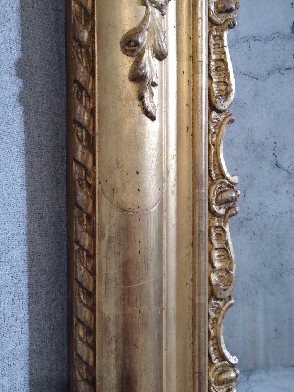 A large rectangular French antique wall mirror featuring a heavily decorated gold leaf frame with floral scroll mouldings. View II