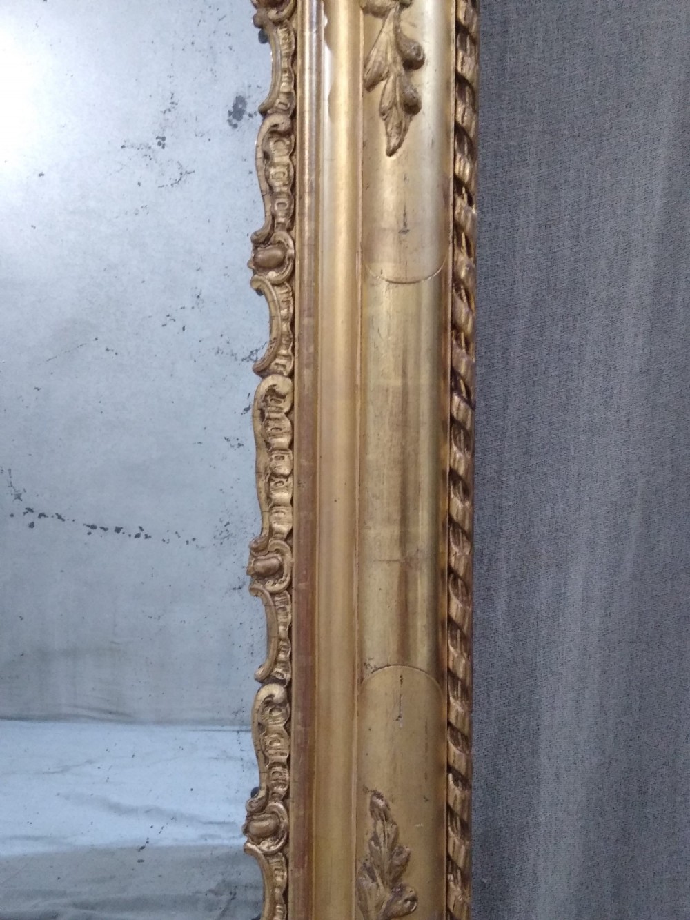 A large rectangular French antique wall mirror featuring a heavily decorated gold leaf frame with floral scroll mouldings. View III