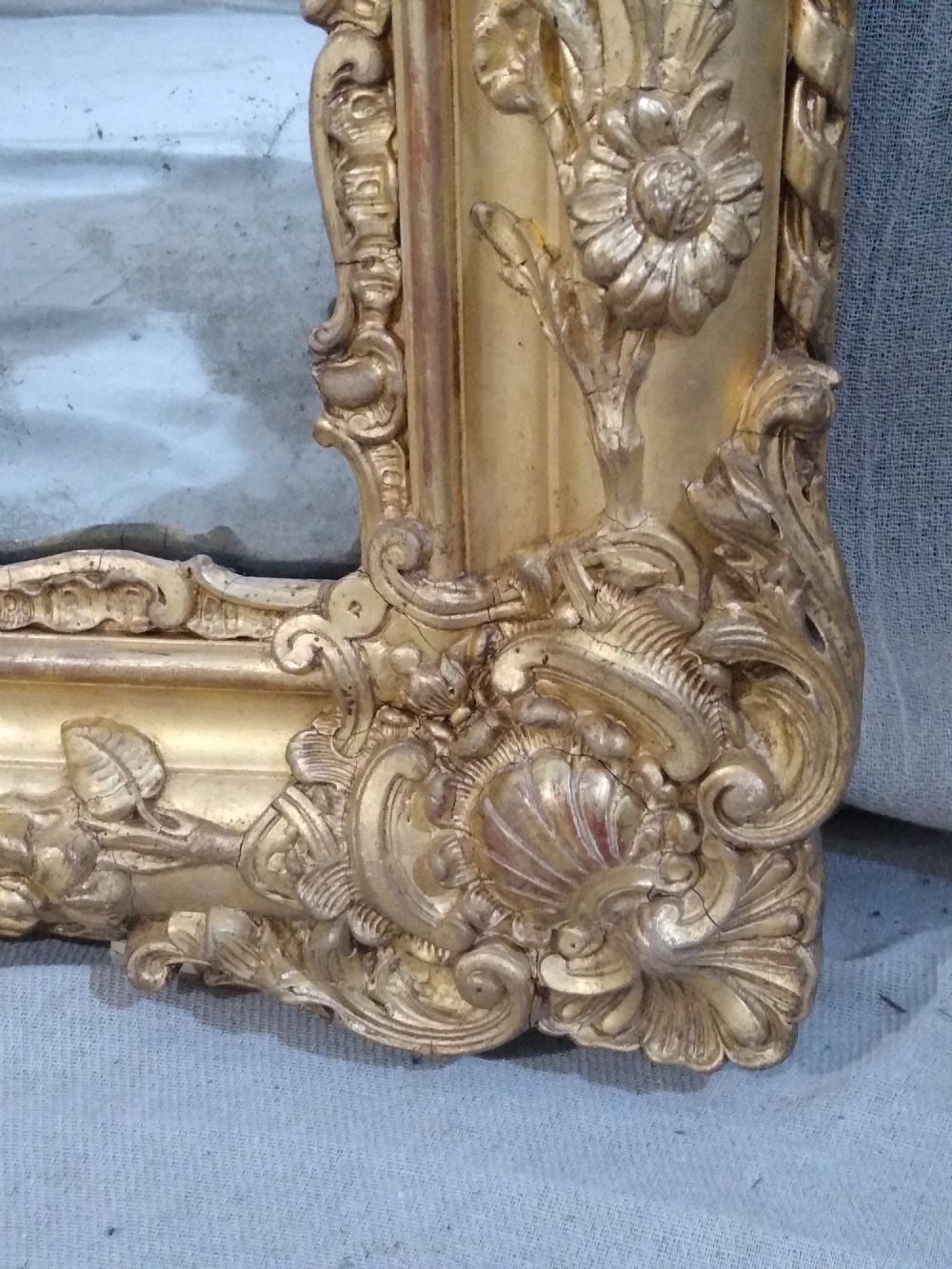 A large rectangular French antique wall mirror featuring a heavily decorated gold leaf frame with floral scroll mouldings. View IV