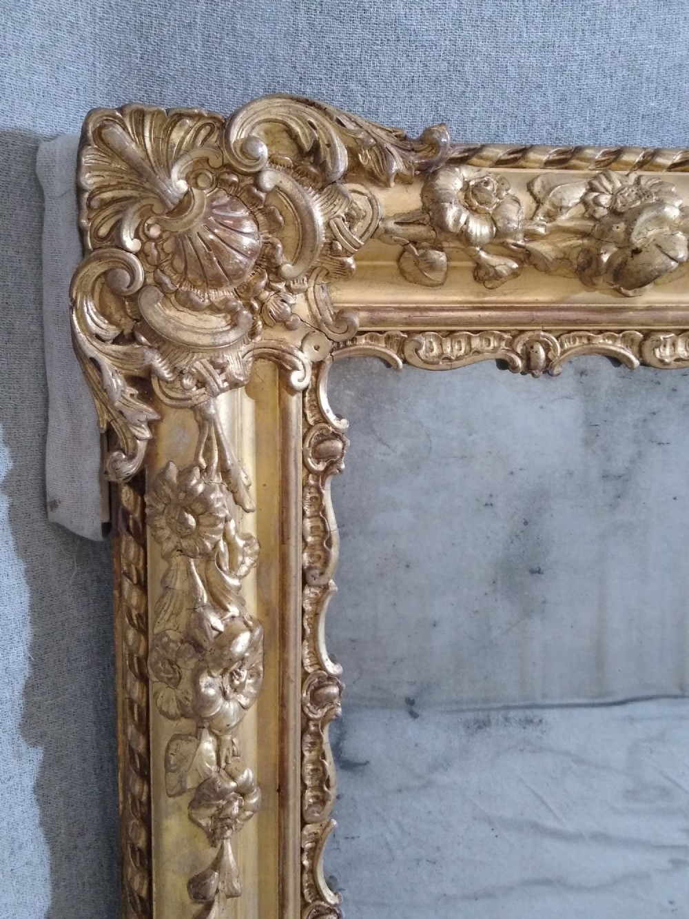 A large rectangular French antique wall mirror featuring a heavily decorated gold leaf frame with floral scroll mouldings. View VII