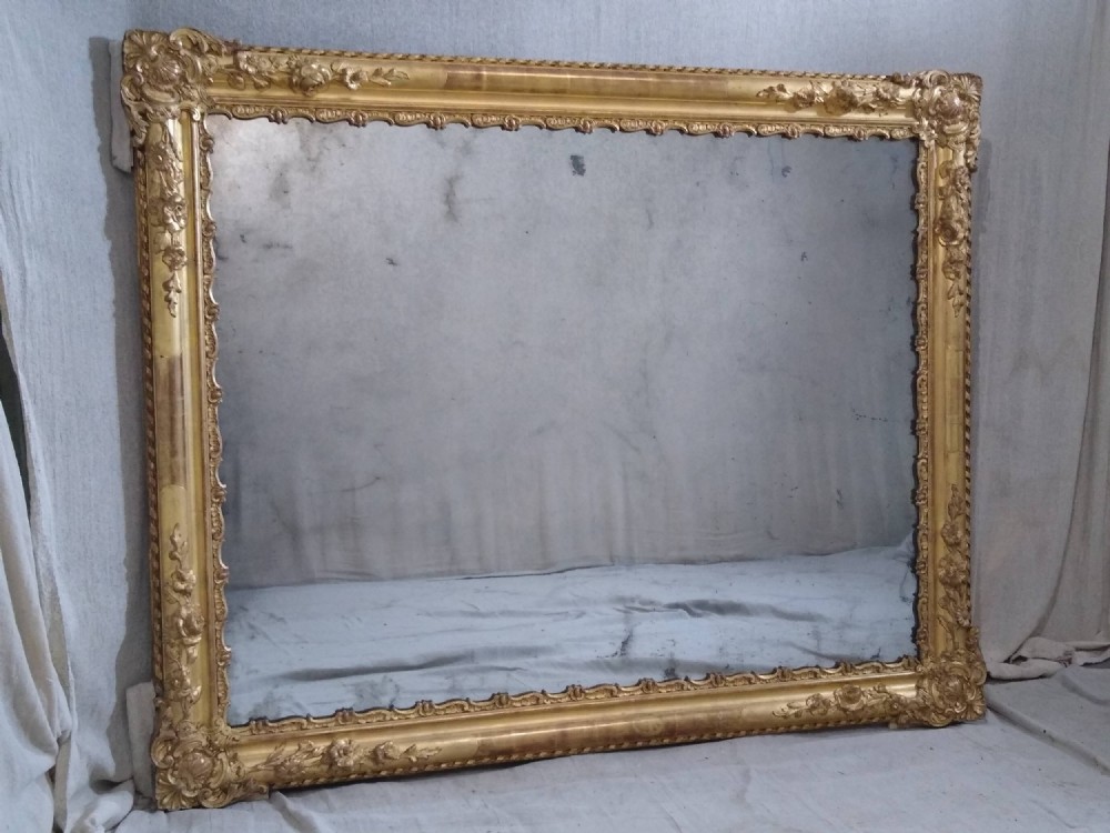 A large rectangular French antique wall mirror featuring a heavily decorated gold leaf frame with floral scroll mouldings. View IX