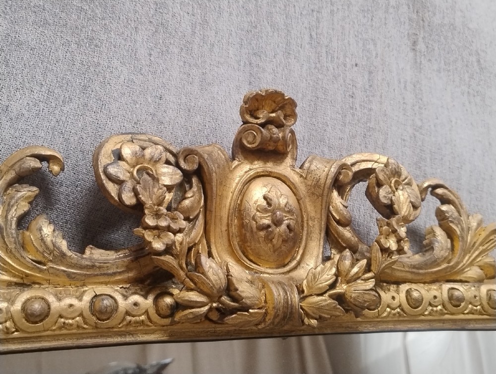 A large antique Victorian arched giltwood overmantel wall mirror featuring elaborate rococo cresting and beaded rim mouldings. View II