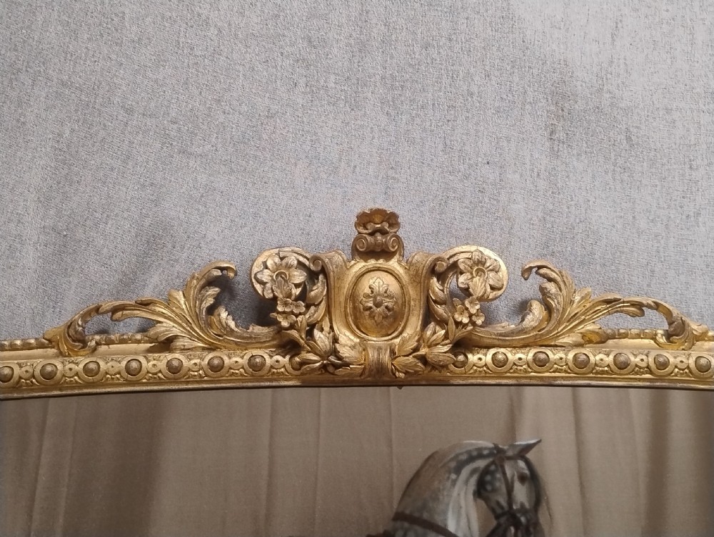 A large antique Victorian arched giltwood overmantel wall mirror featuring elaborate rococo cresting and beaded rim mouldings. View III