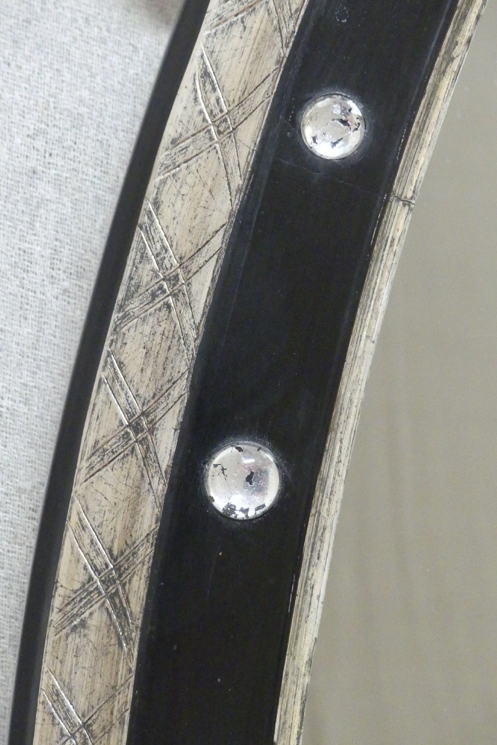 An antique oval wall mirror featuring a black ebonised band inset with round glass studs, framed by an engraved silvered border. View II