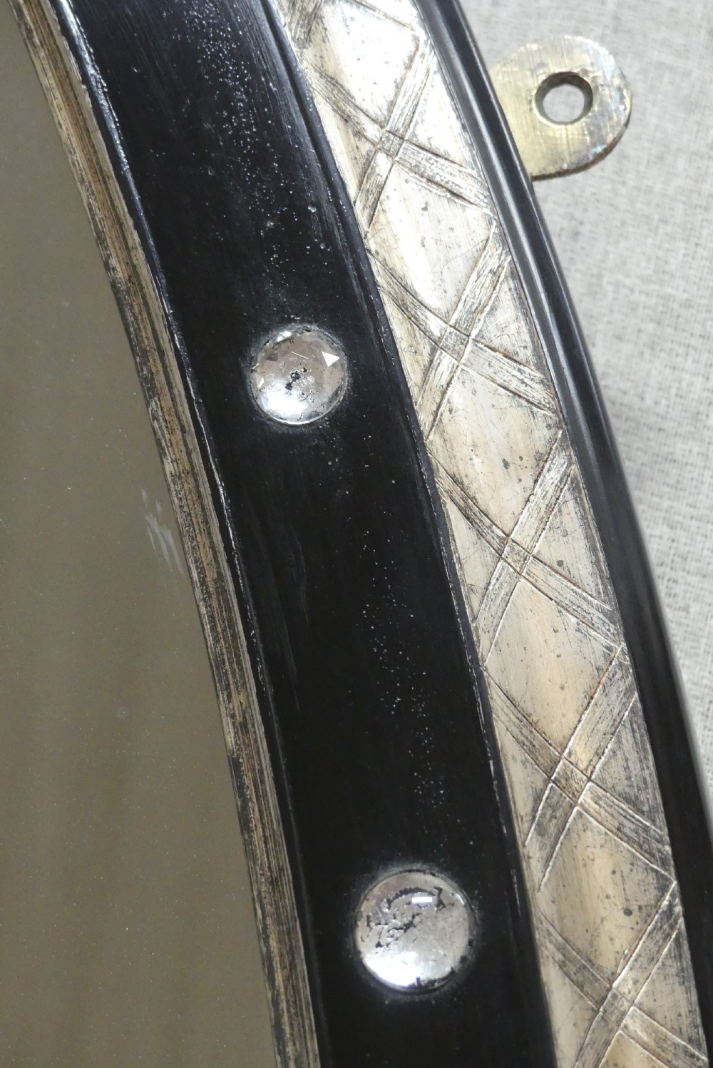 An antique oval wall mirror featuring a black ebonised band inset with round glass studs, framed by an engraved silvered border. View III