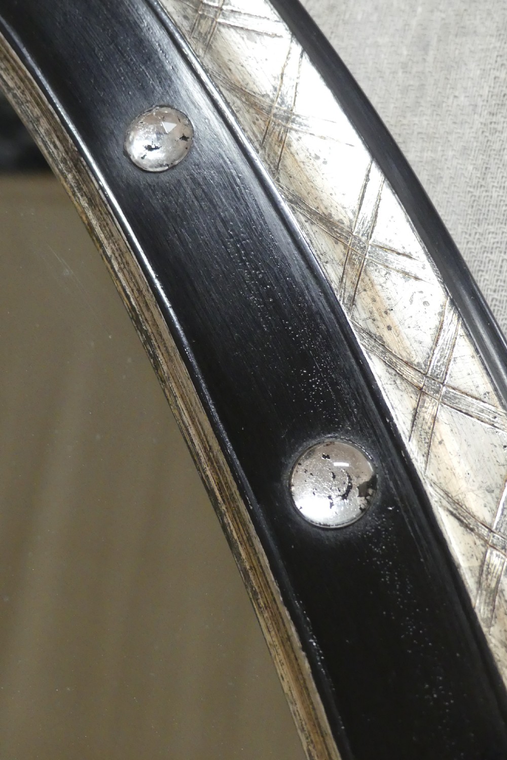 An antique oval wall mirror featuring a black ebonised band inset with round glass studs, framed by an engraved silvered border. View IV