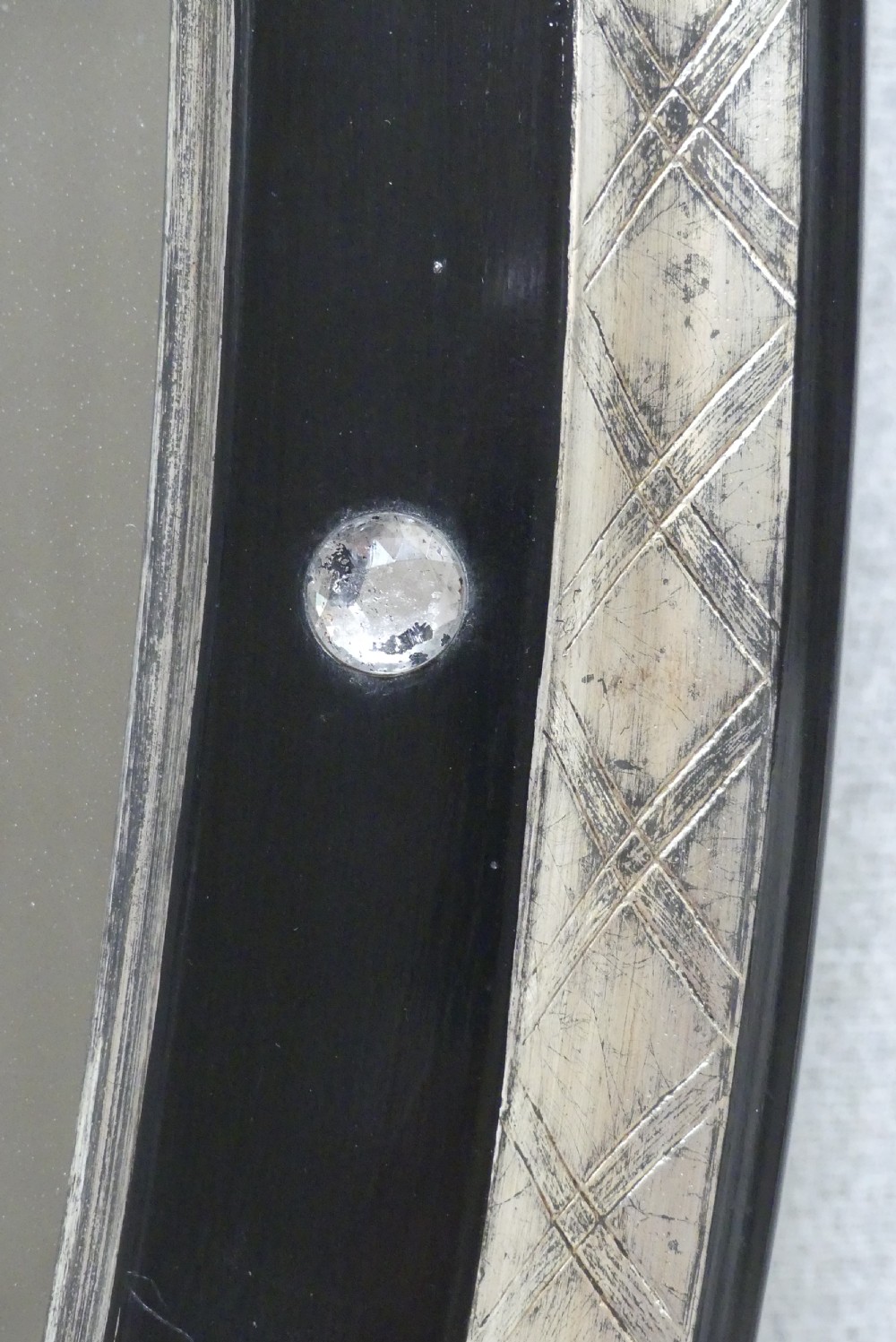 An antique oval wall mirror featuring a black ebonised band inset with round glass studs, framed by an engraved silvered border. View V