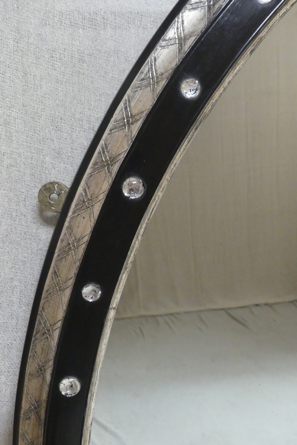 An antique oval wall mirror featuring a black ebonised band inset with round glass studs, framed by an engraved silvered border. View VI