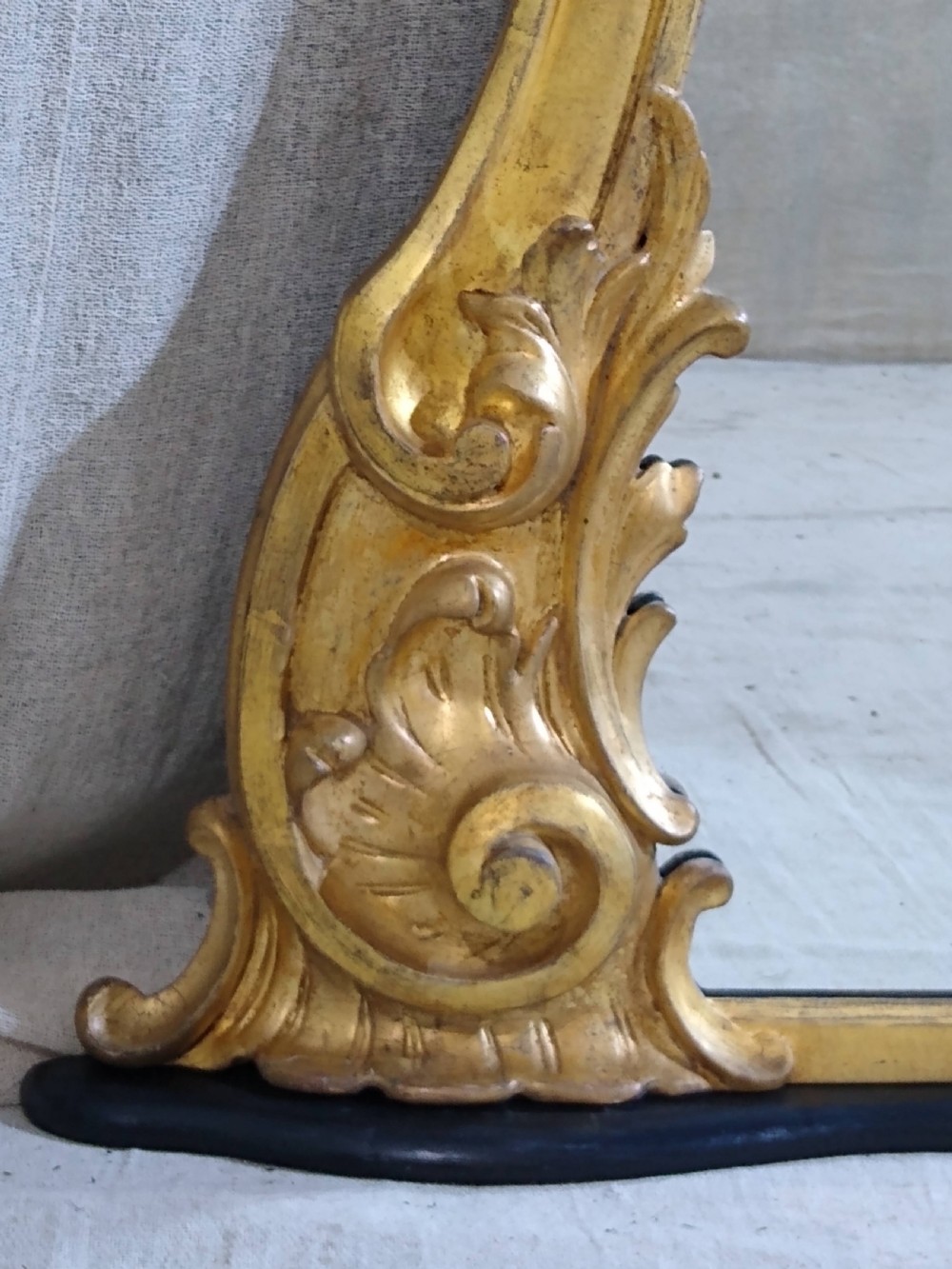 A large Victorian giltwood overmantel mirror featuring an arched top frame moulding and carved acanthus leaf scroll embellishments at the lower base corners. View V