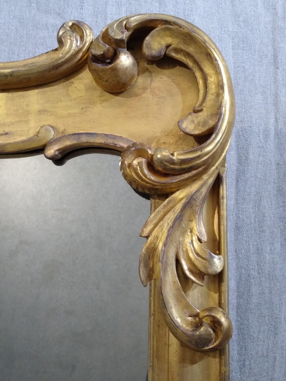 A large mid-nineteenth century giltwood overmantel mirror featuring elaborate scrolled cresting and decorative corner accents. View III