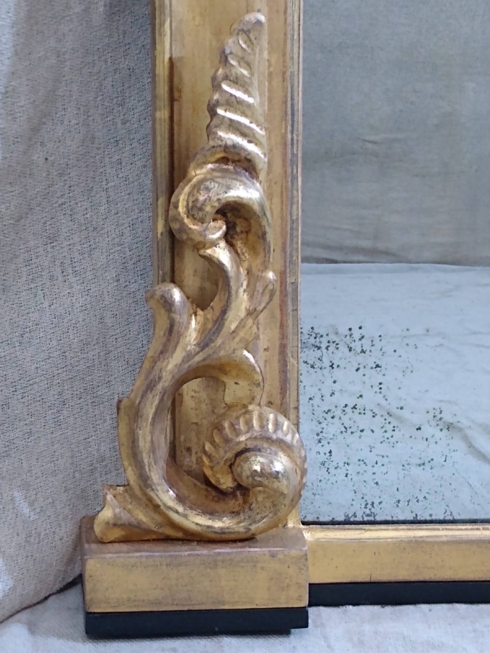 A large mid-nineteenth century giltwood overmantel mirror featuring elaborate scrolled cresting and decorative corner accents. View VI