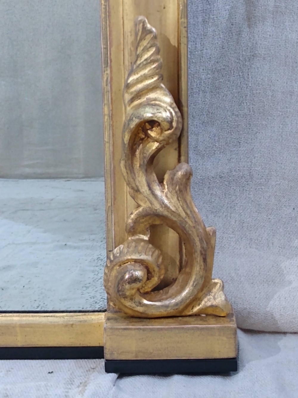 A large mid-nineteenth century giltwood overmantel mirror featuring elaborate scrolled cresting and decorative corner accents. View VII