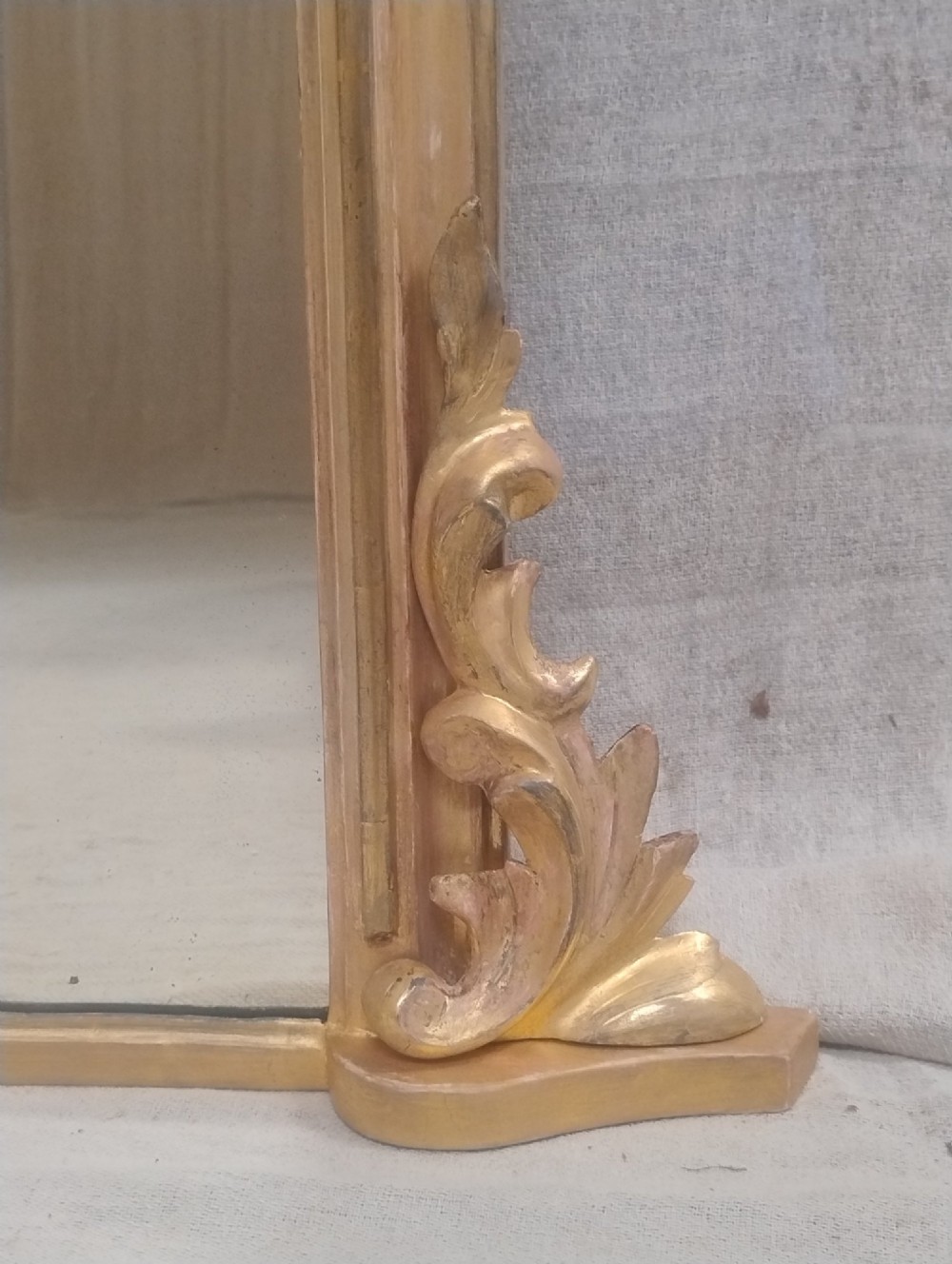 An arched Victorian overmantel mirror with a gilded finish, decorated with a central carved shell crest and scrolled side feet. View II