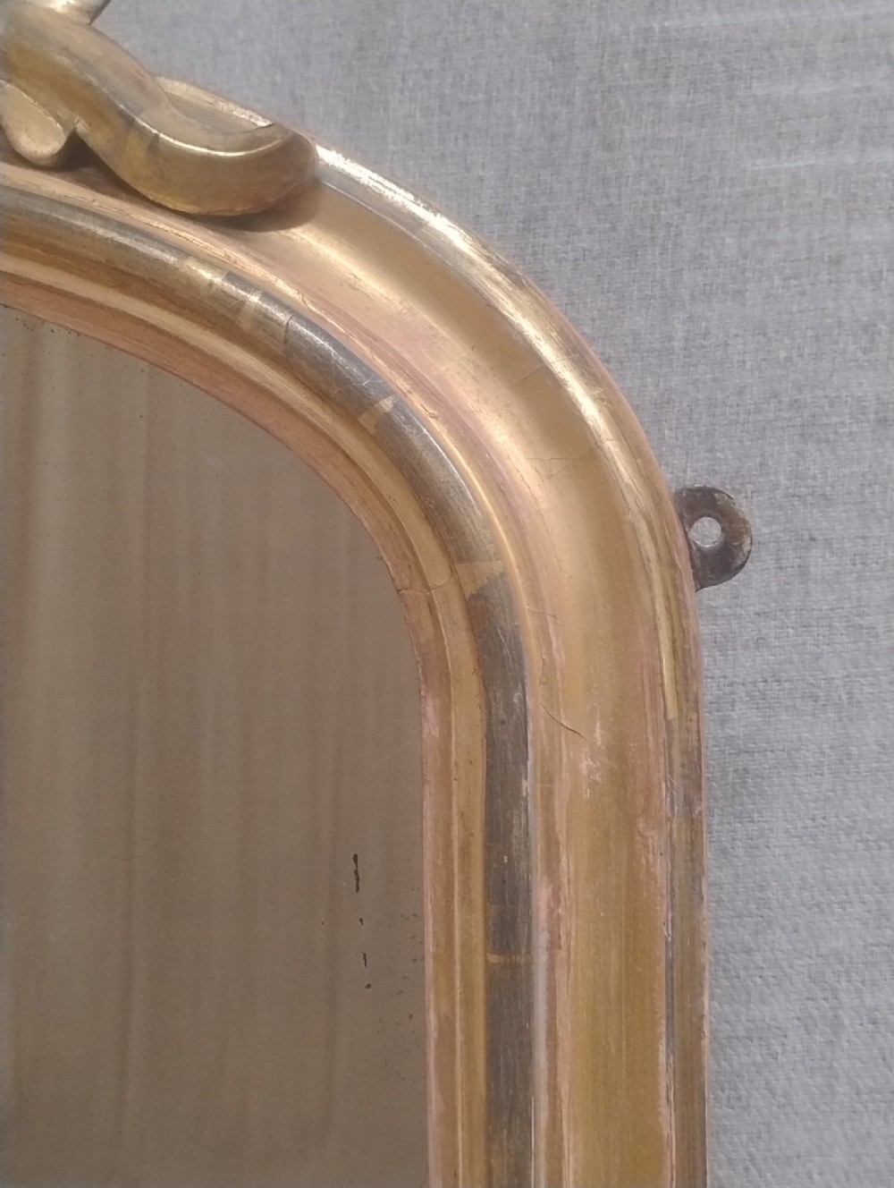 An arched Victorian overmantel mirror with a gilded finish, decorated with a central carved shell crest and scrolled side feet. View III