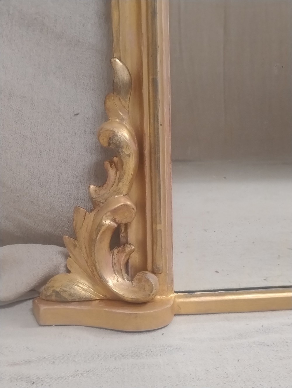 An arched Victorian overmantel mirror with a gilded finish, decorated with a central carved shell crest and scrolled side feet. View IV