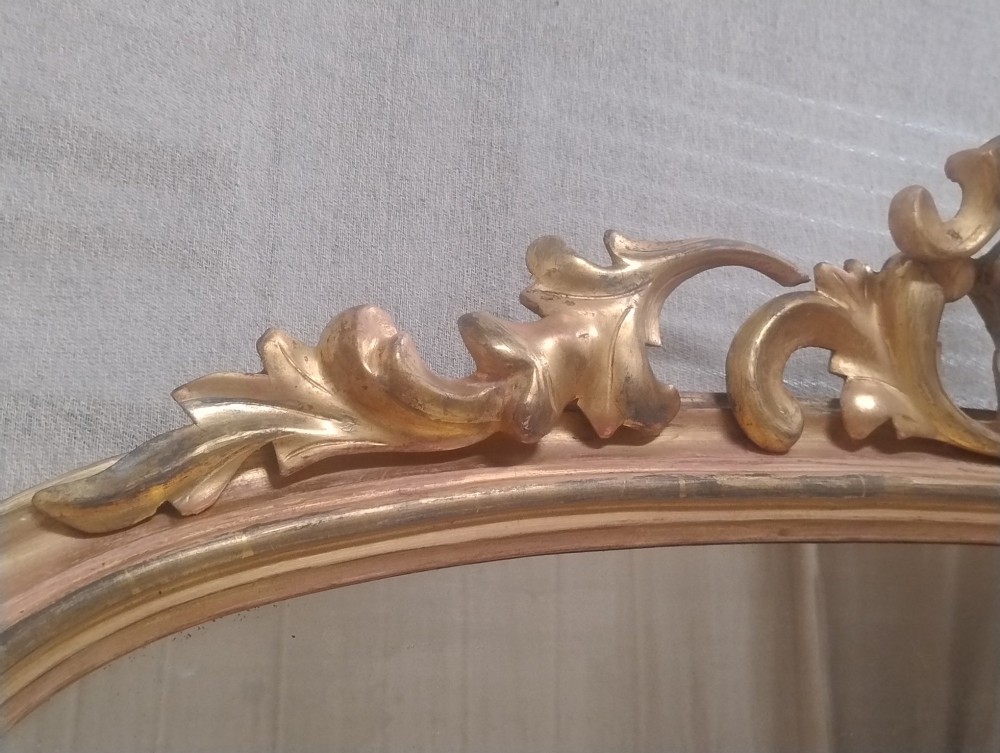 An arched Victorian overmantel mirror with a gilded finish, decorated with a central carved shell crest and scrolled side feet. View V