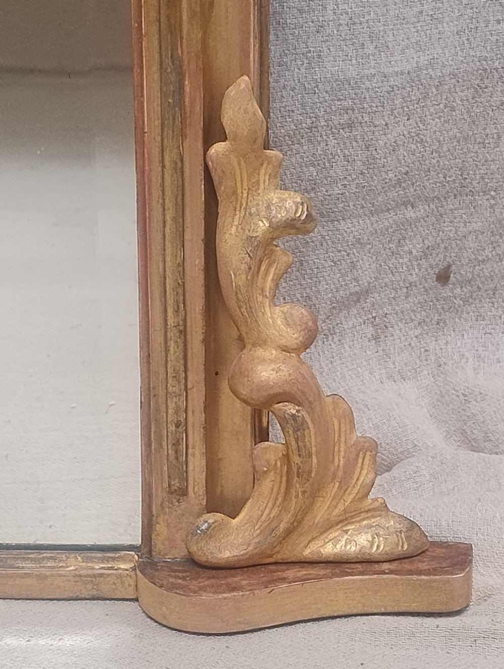 A large rectangular antique gilt overmantel mirror featuring rounded upper corners, moulded frame, and carved acanthus scroll feet at the base. View V