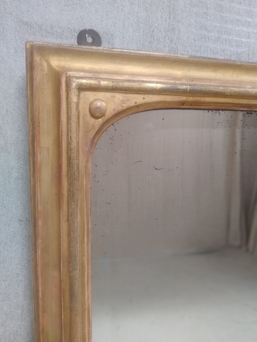 A large rectangular antique gilt overmantel mirror featuring rounded upper corners, moulded frame, and carved acanthus scroll feet at the base. View VI