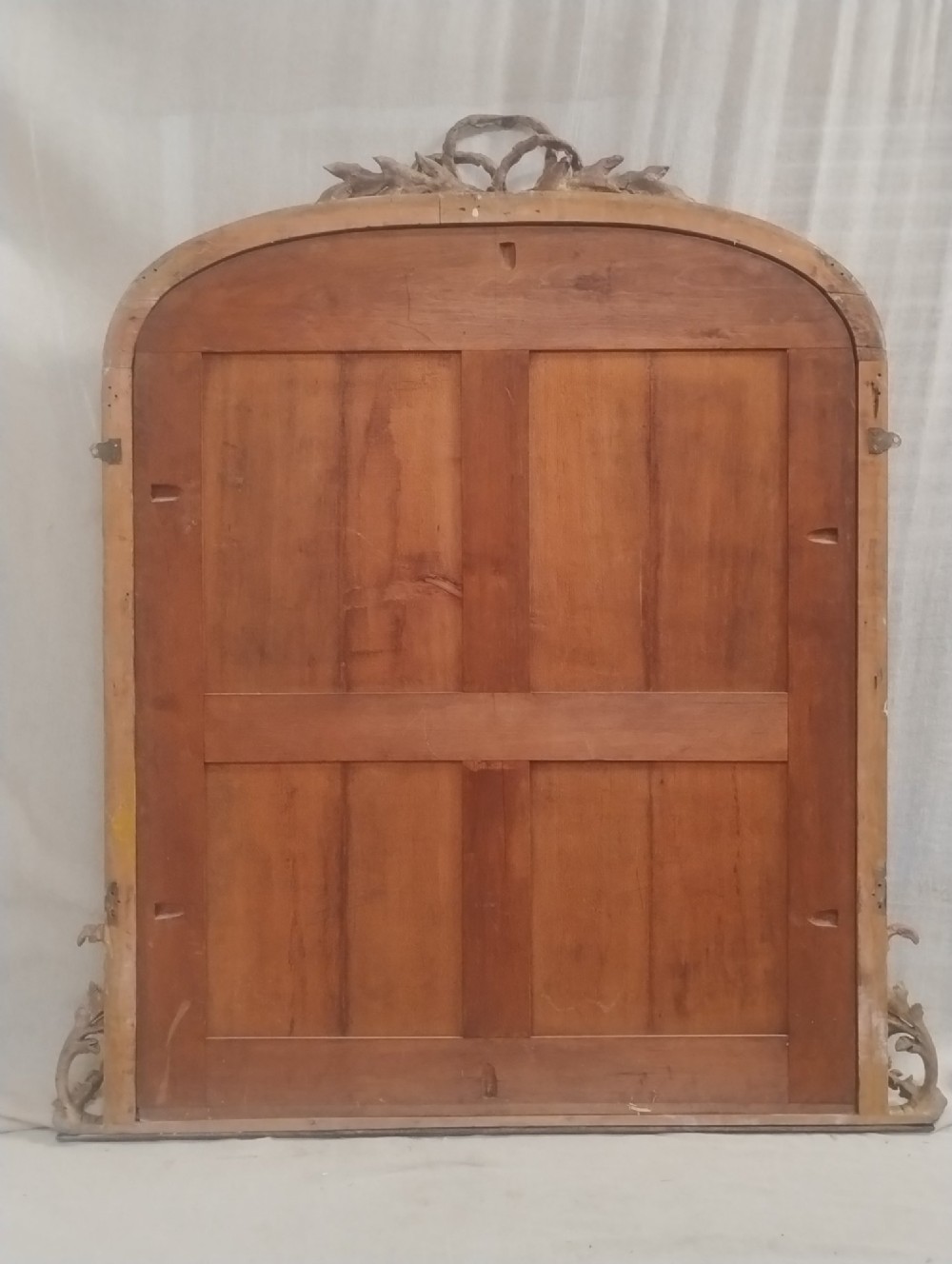 A large Victorian giltwood overmantel mirror featuring an arched top decorated with a carved ribbon bow crest and lower scrolled side supports. View II