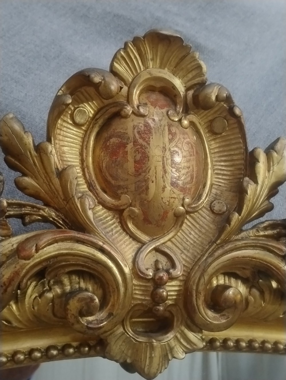 A tall French giltwood mirror featuring a carved floral cartouche cresting, arched top, and moulded beaded inner border. View IV