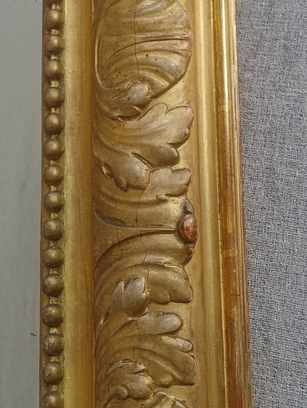 A tall French giltwood mirror featuring a carved floral cartouche cresting, arched top, and moulded beaded inner border. View VIII