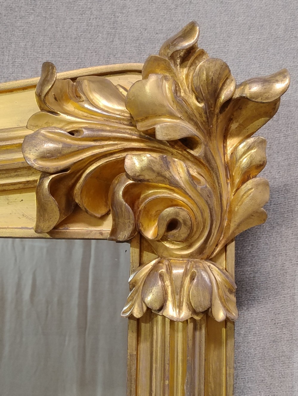 A large nineteenth-century giltwood overmantel mirror featuring carved acanthus leaf cresting and fluted column pilasters. View V