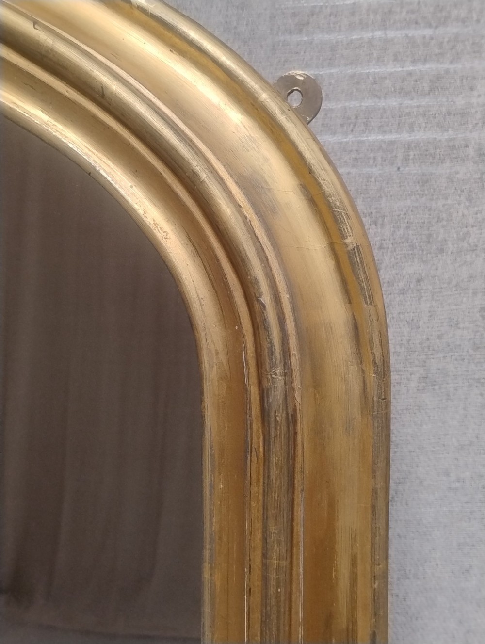 An antique Victorian arched overmantel mirror featuring a moulded gold giltwood frame with subtle bottom side corbels. View V
