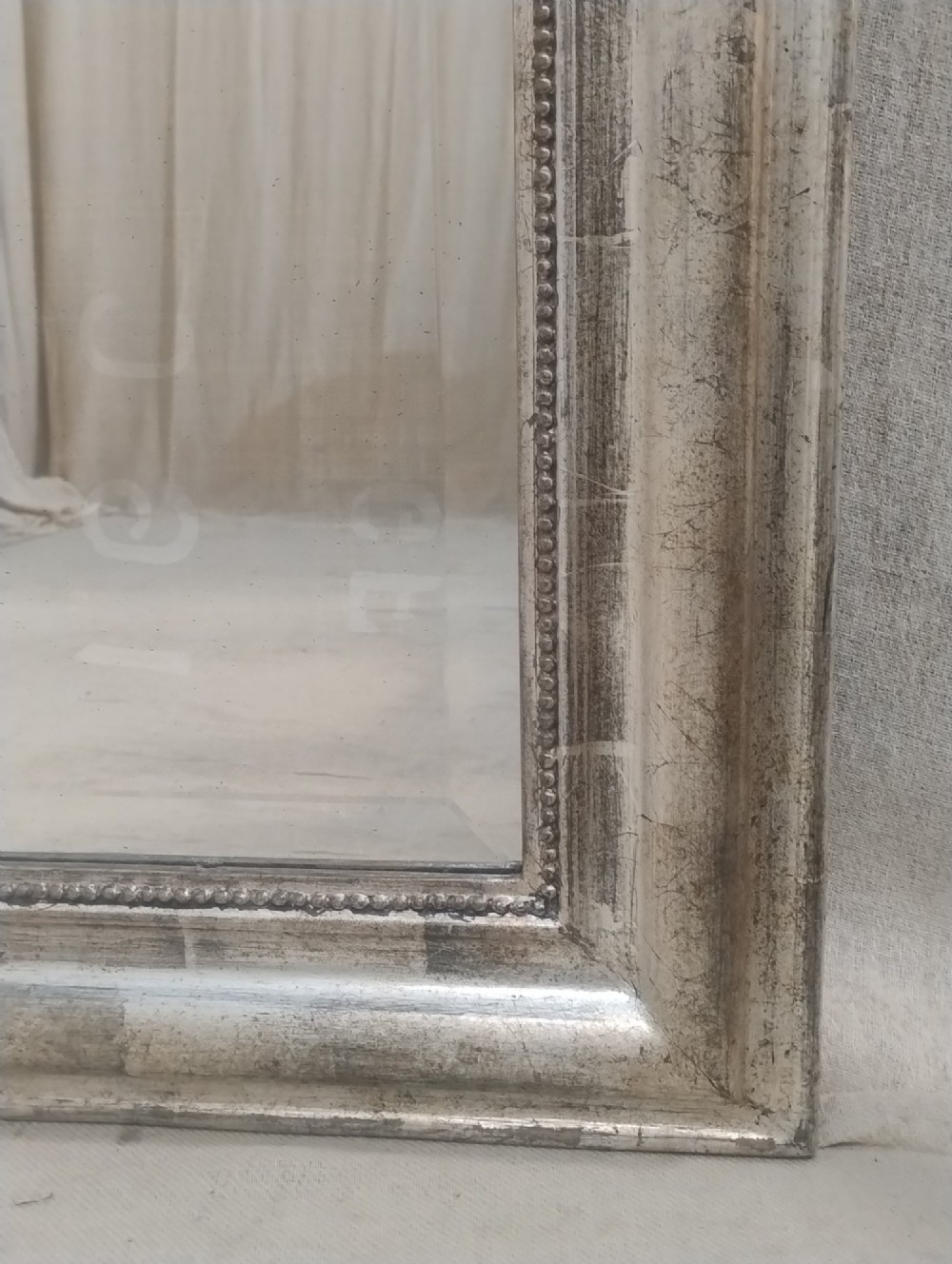 A large nineteenth-century French wall mirror featuring a silver gilt wooden frame, rounded top corners, beaded inner border, and an ornate carved shell crest. View VI