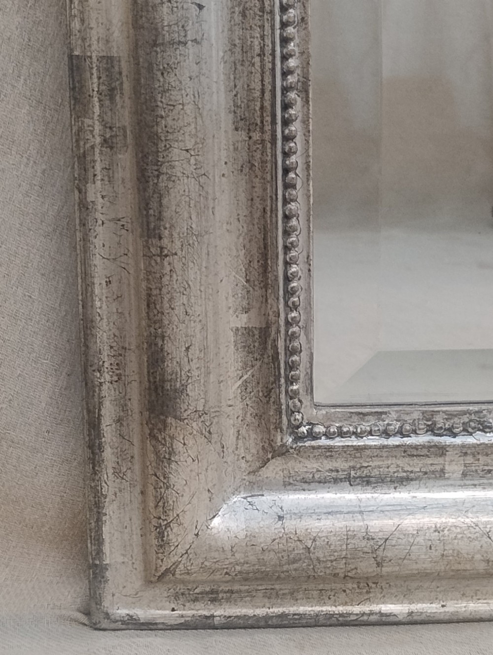 A large nineteenth-century French wall mirror featuring a silver gilt wooden frame, rounded top corners, beaded inner border, and an ornate carved shell crest. View VII