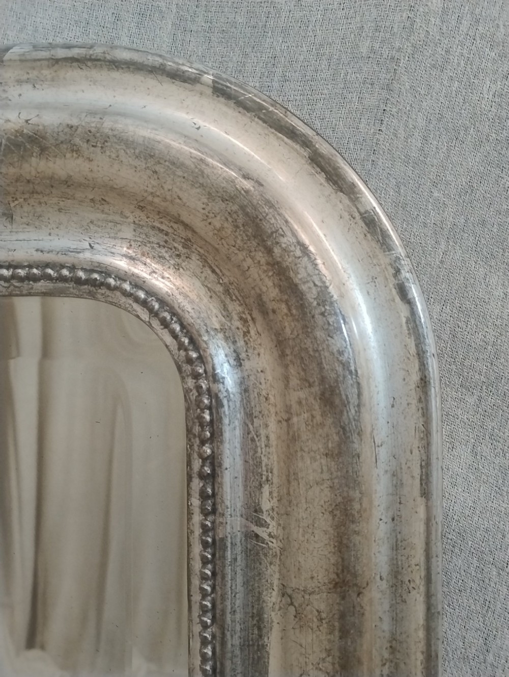 A large nineteenth-century French wall mirror featuring a silver gilt wooden frame, rounded top corners, beaded inner border, and an ornate carved shell crest. View IX