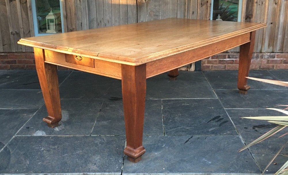 A rectangular Victorian oak farmhouse kitchen table featuring tapered legs with scroll feet and an end drawer with a brass drop handle.