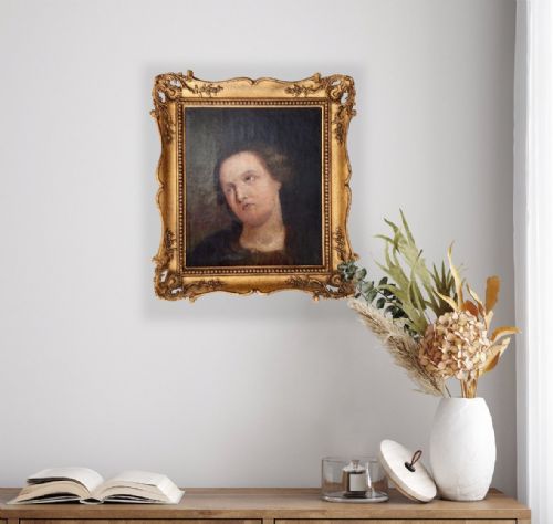 fig 1. An oil painting depicting a head and shoulders portrait of a female figure looking upward, set within an ornate carved giltwood frame.