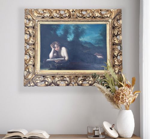 fig 2. An oil painting of Mary Magdalen reclining in a landscape while reading a book, set within a carved gilt frame.