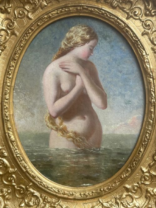 fig 1. An oval Victorian oil painting depicting a mythological blonde Nereid emerging from sea water, set within a heavily carved rectangular gold gilt frame.