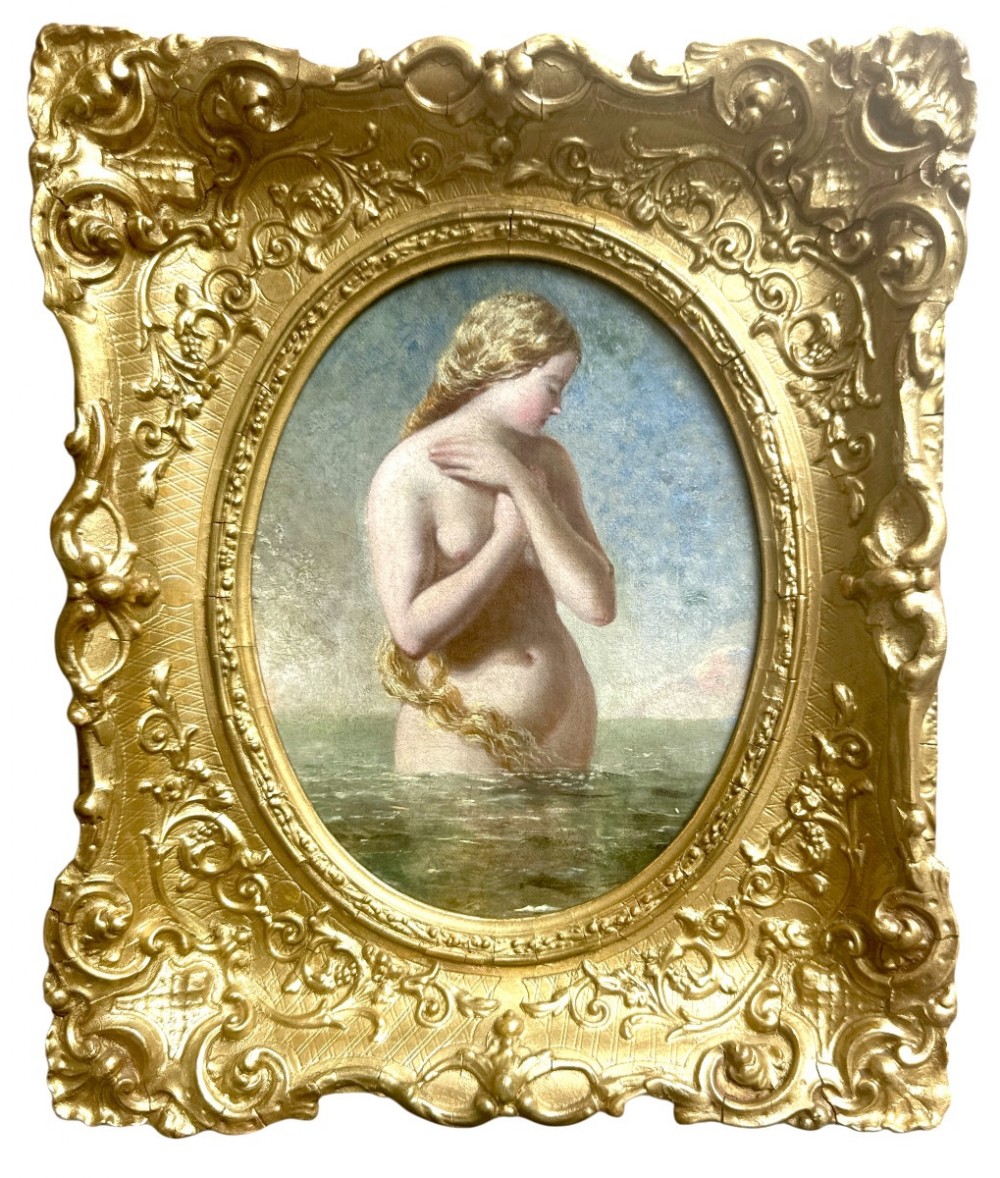 An oval Victorian oil painting depicting a mythological blonde Nereid emerging from sea water, set within a heavily carved rectangular gold gilt frame.