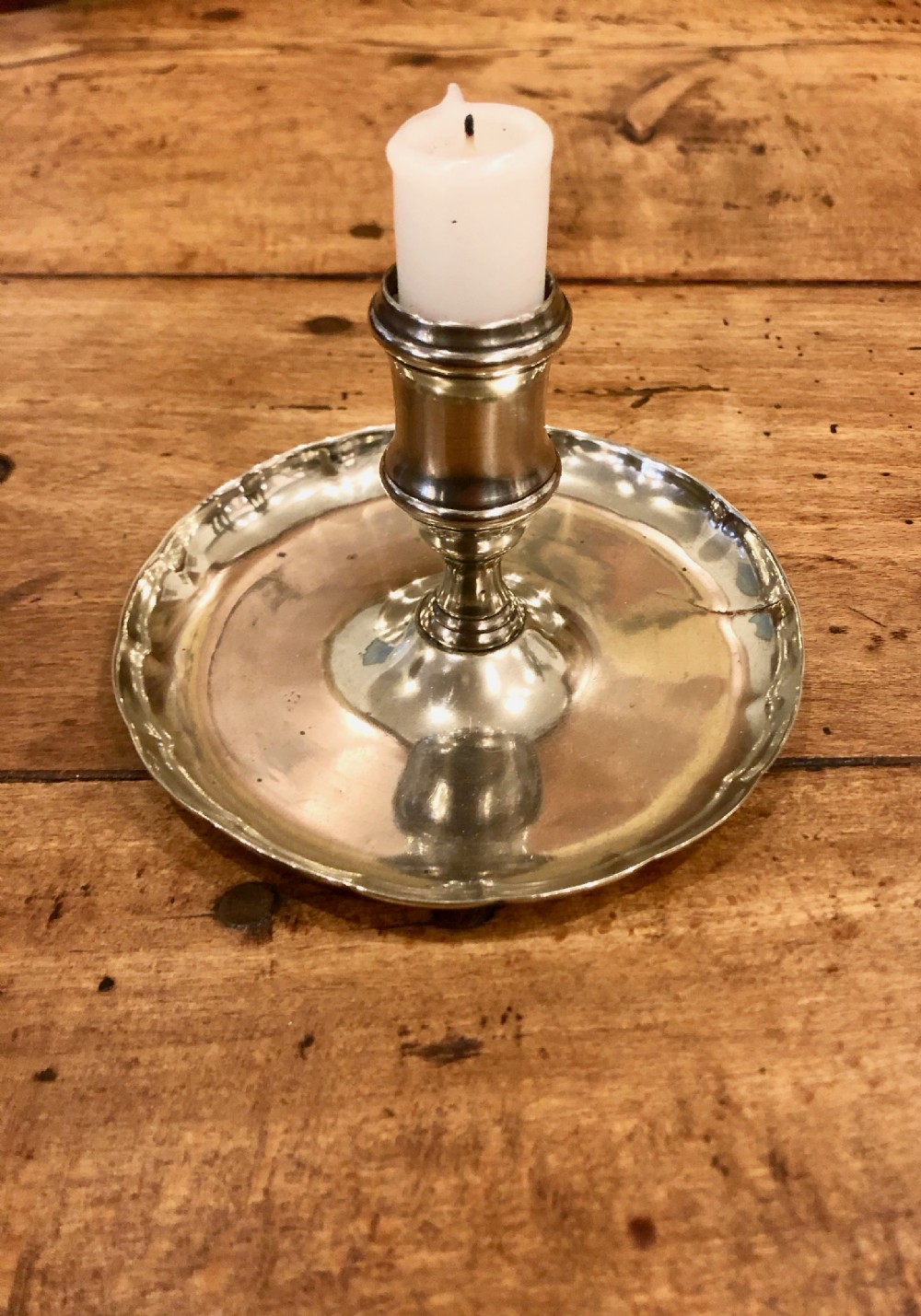 An 18th-century silver-toned paktong chamber candlestick featuring a central tapered candle socket set on a circular tray with a scalloped edge.